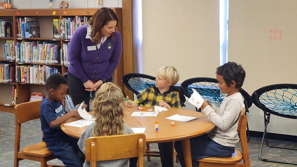 adult talking to students at a table