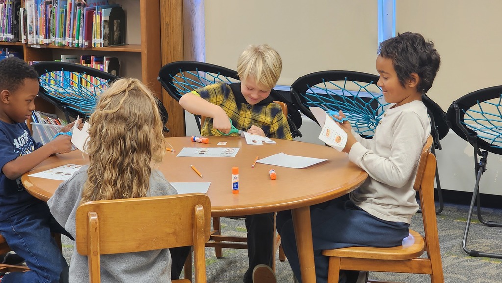 students sitting at table cutting paper