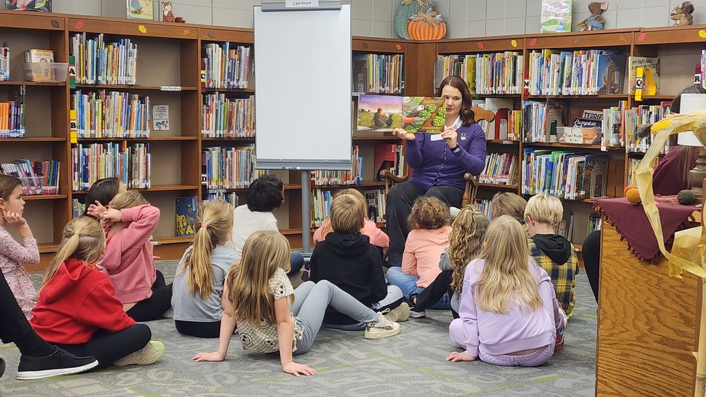 students listening as adult reads a book to them