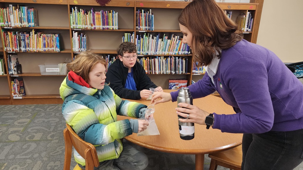 adult helping students with science experiment