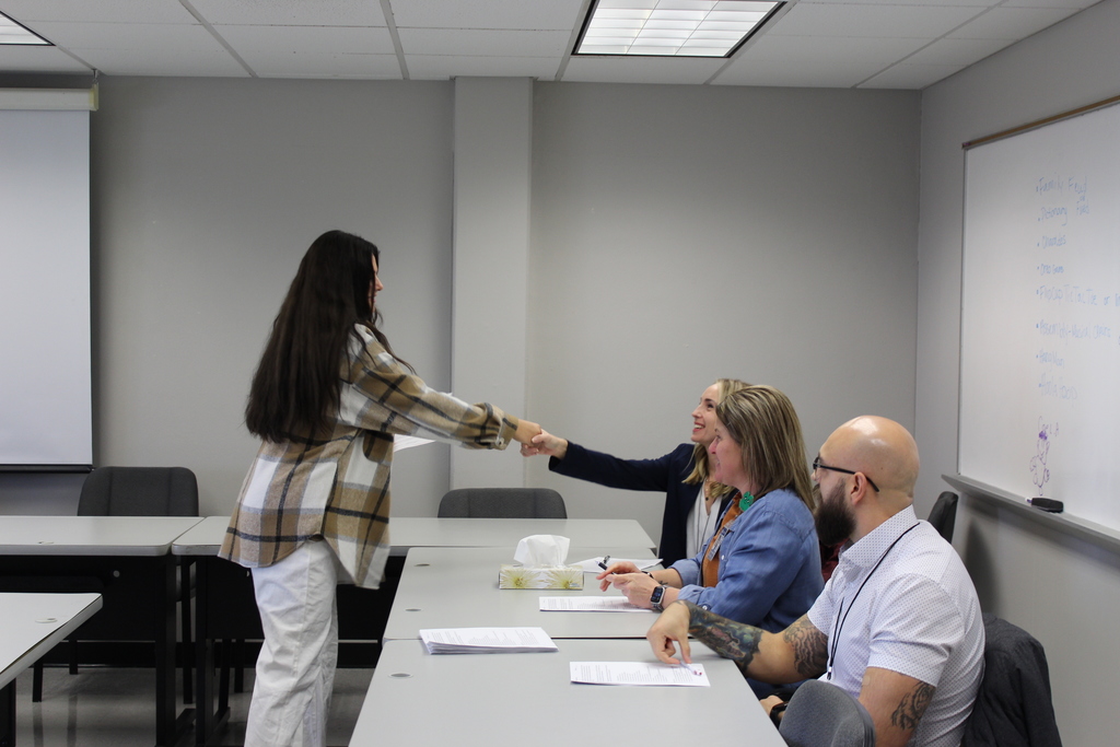 student shaking hands with seated adult