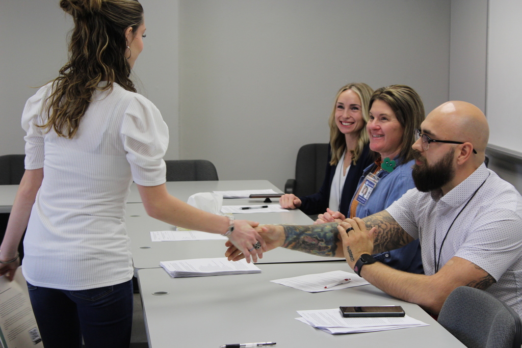 student shaking hands with adults