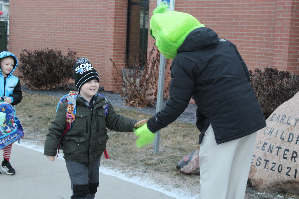 student greeting adult in grinch costume
