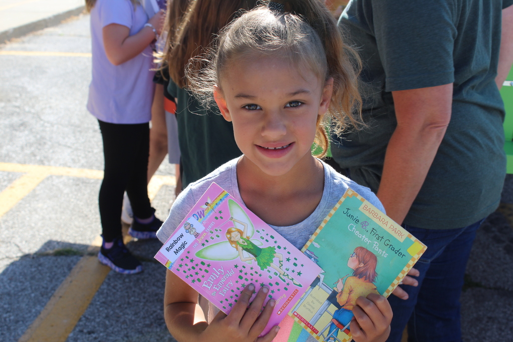 child smiling while holding books