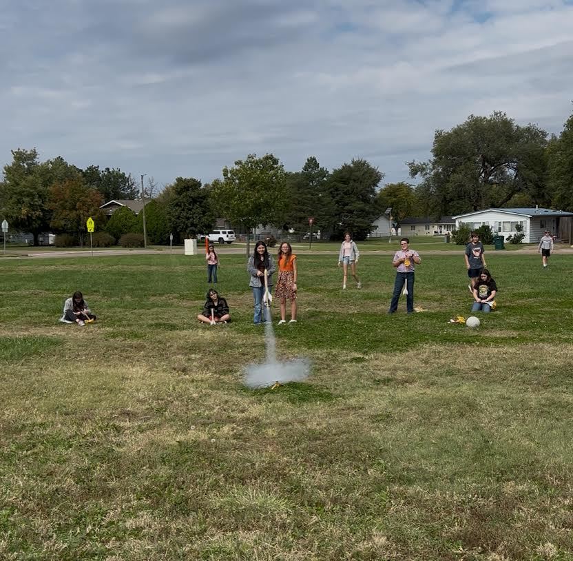 students stand behind rocket launch