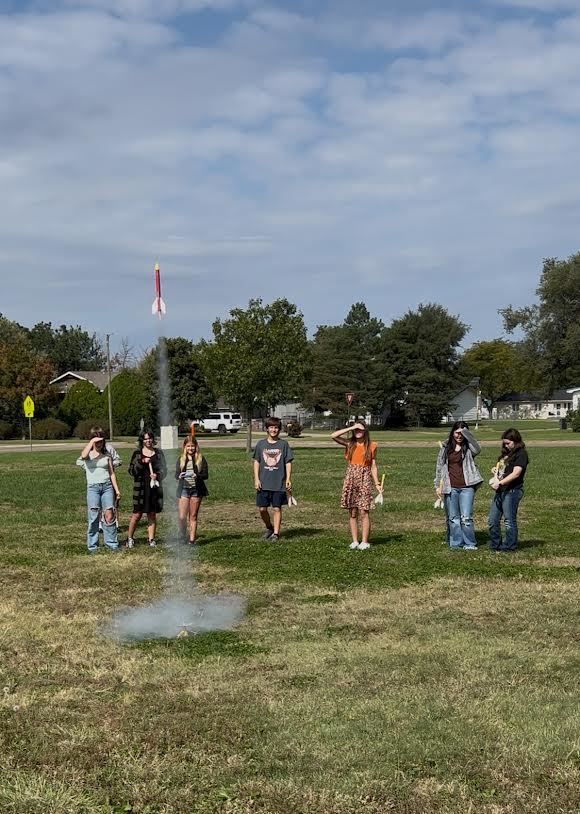 students stand behind rocket launch