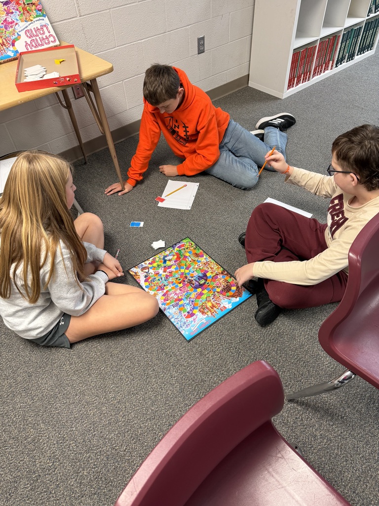 Three young people are seated on a carpeted floor, engaging in a puzzle. One person is wearing glasses.