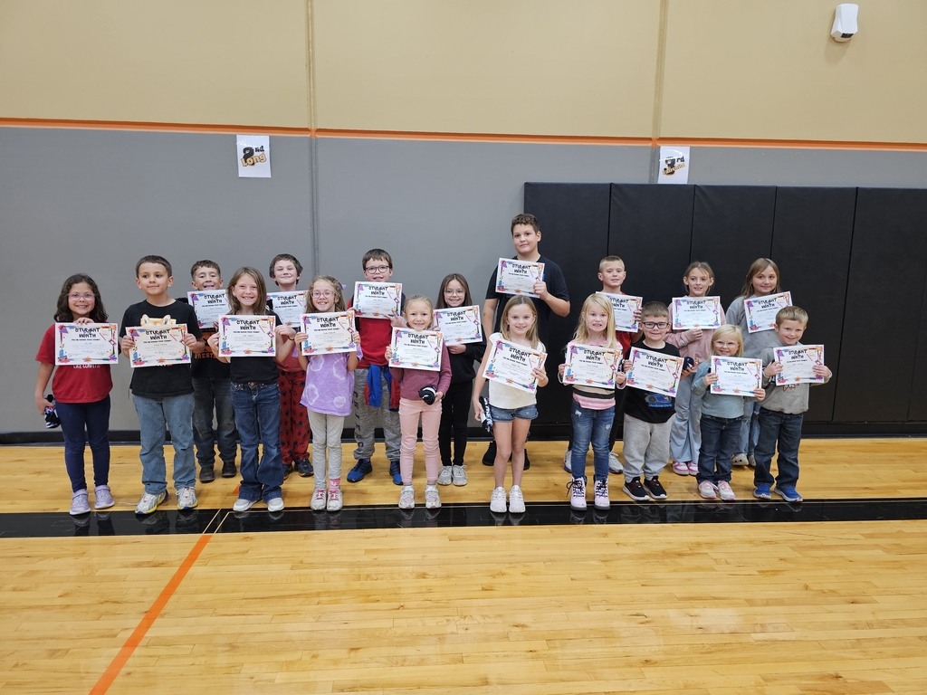 Students holding certificates stand on a basketball court; a coach stands in the middle.