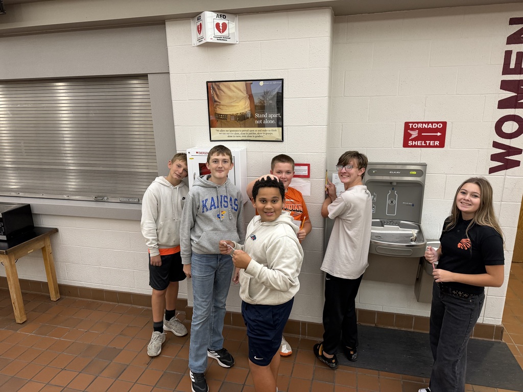 6 students in front of a drinking fountain smiling for the camera. 