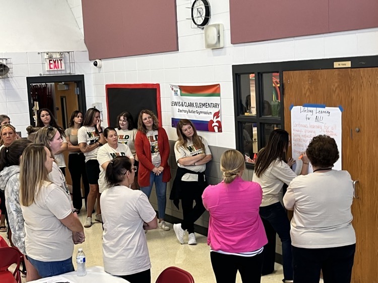 LCE staff around an anchor chart, writing what comes to mind regarding the value of LIFELONG LEARNING!