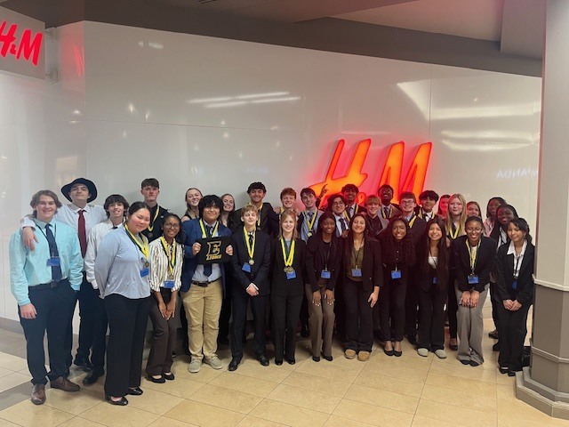 FBLA students posing together in front of the H and M sign at Mid Rivers Mall