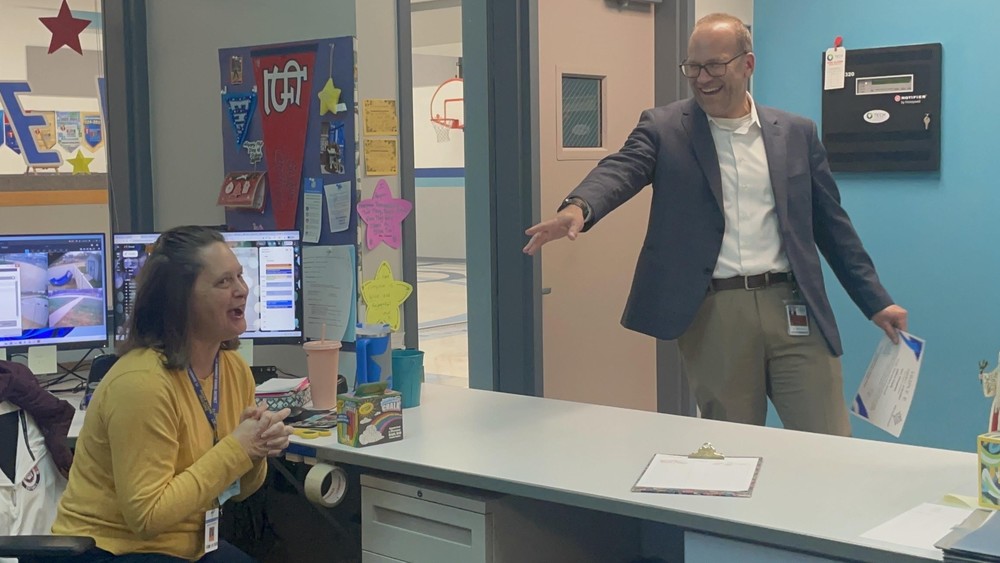 Office professional reacts with great suprise as Superintentdent smiles and announces her special recognition