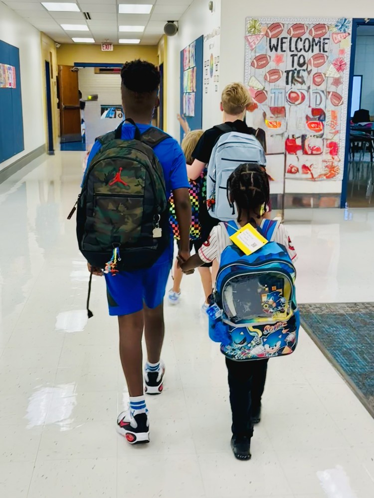 Siblings walk down the hallways hand in hand