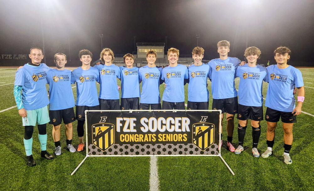 Soccer Seniors posing in front of their senior banner
