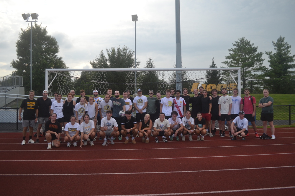Soccer alumni posing for a group photo in front of a goal