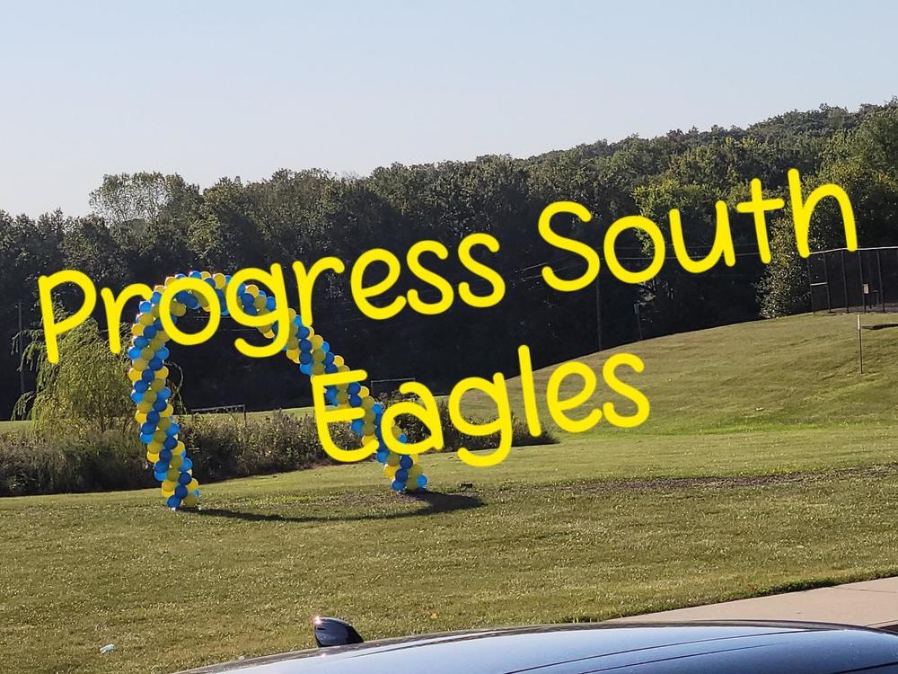 a field with a balloon arch says progress south eagles