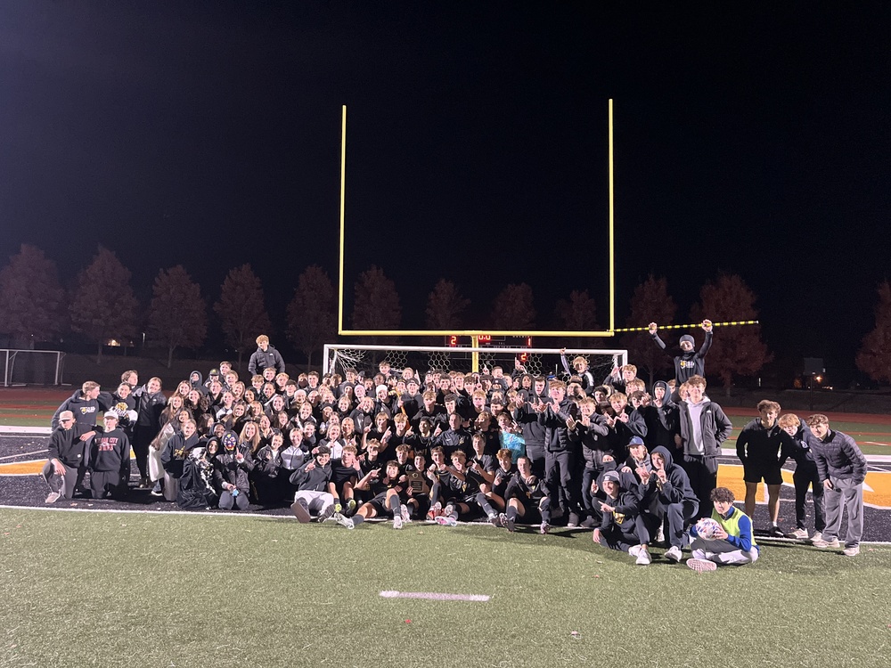 The 600 posing with our boys soccer team holding the district champion plaque!