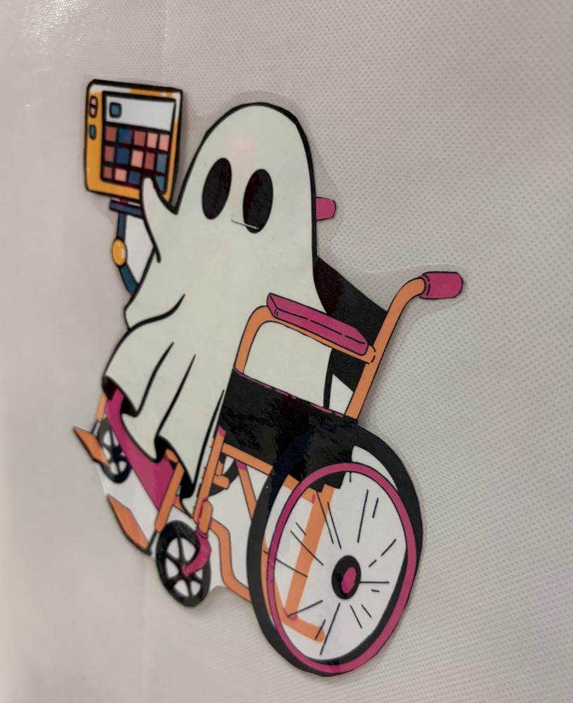 A white ghost in a wheel chair holding a multi-colored Alternative/Augmentative Communication device