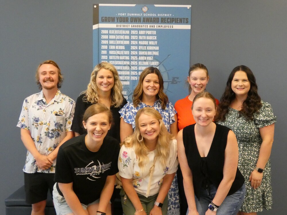 Teachers pose in front of GYOT award board