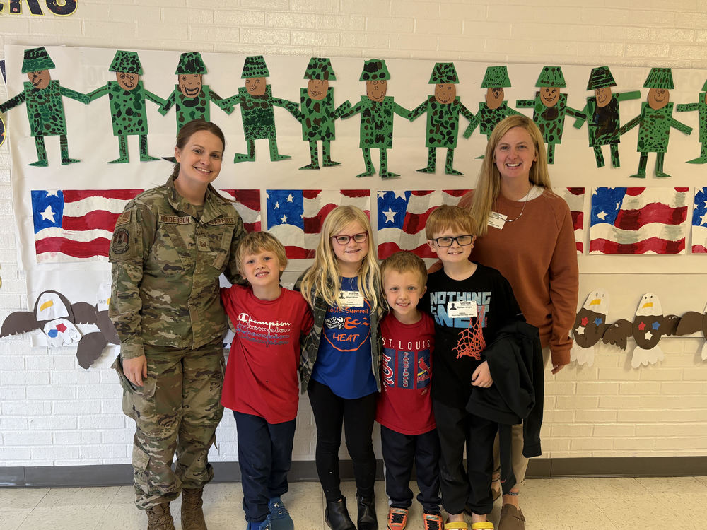 A soldier in uniform standing with 4 her family