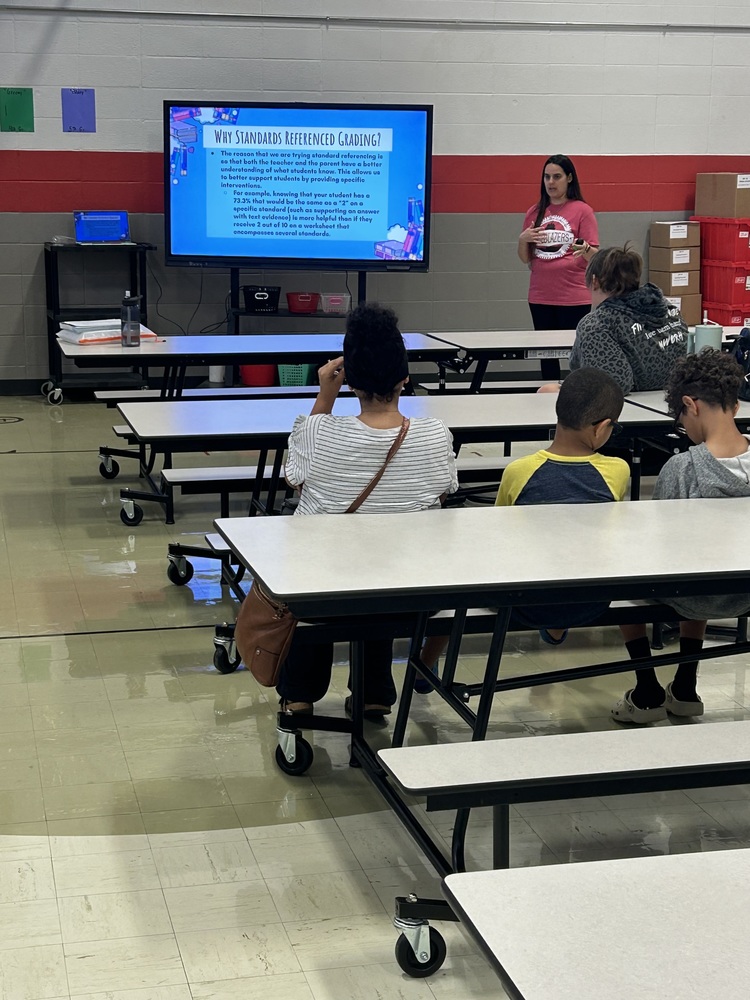 Ms. Lemmons in a red tshirt explaining information to a group of parents
