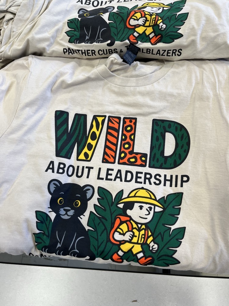 LCE Staff tshirt. Gray/cream color, WILD ABOUT LEADERSHIP written on the front in multiple colors. A small cartoon panther cub and explorer below the wording.