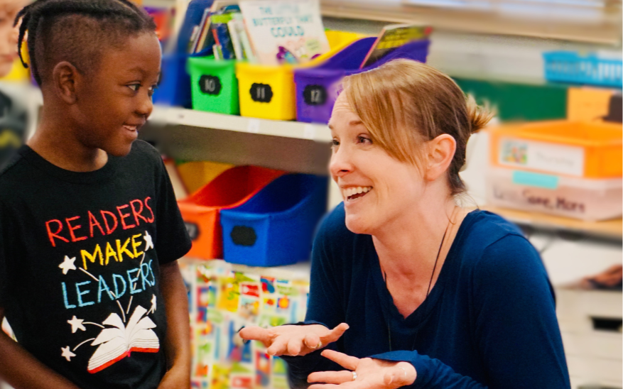 Teacher and student smile as they wonder together about what they just read in kindergarten