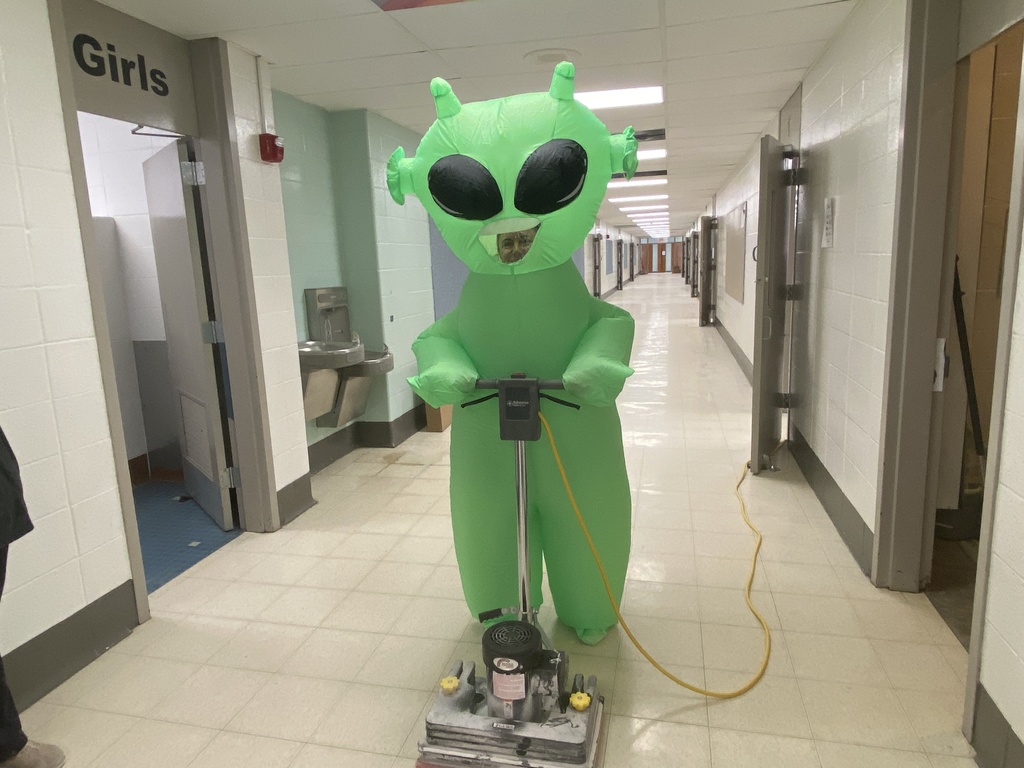 Green alien waxing the floor