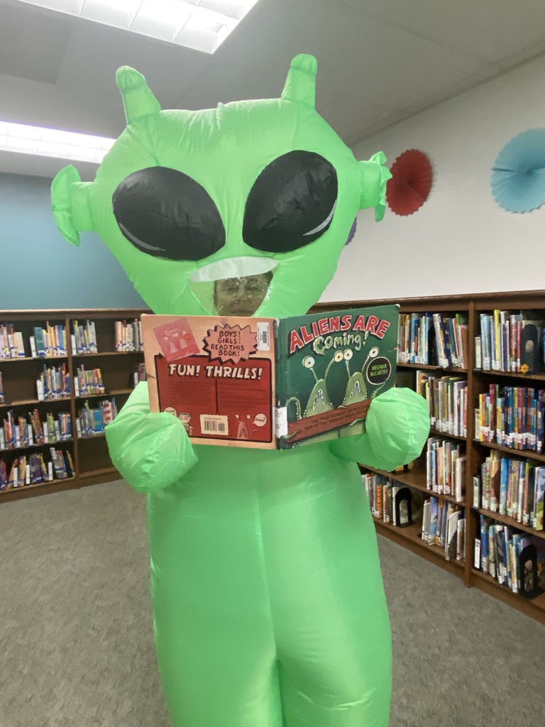 Green alien reading a book