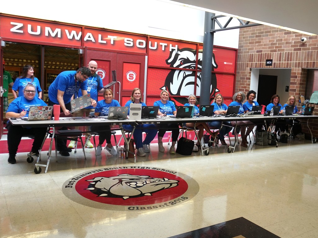 A fleet of nurses lined up at a  long table gets some last minute tech support as they wait for doors to open at the Back to School Bash