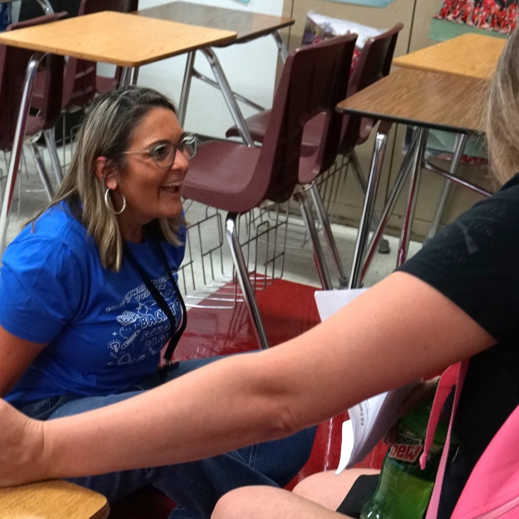 FZ staff member listens closely and  smiles from ear to ear as she helps a student try on new shoes