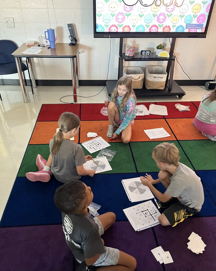 math centers! students playing math games on a multicolor rug.