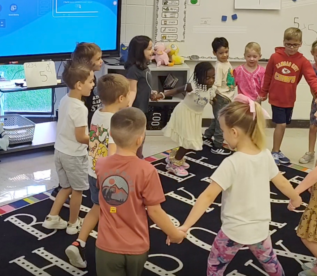 kindergarten students sing and dance with Ring Around the Rosy