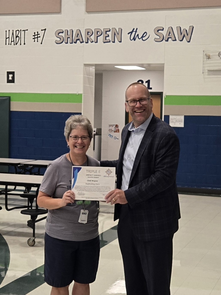 Dr. Stop. Pierre presents the triple E award to Mrs. Wagner at school on Wednesday.