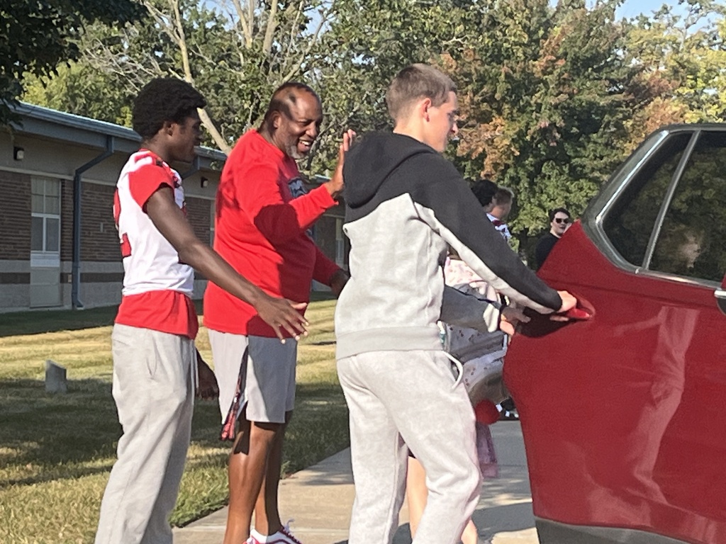 Football players and head coach in the car line