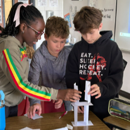 Three students work to build the tallest paper tower in their homeroom