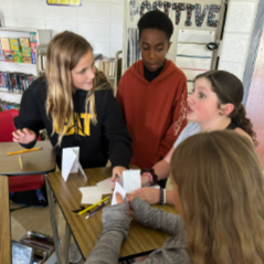Three students work to build the tallest paper tower in their homeroom