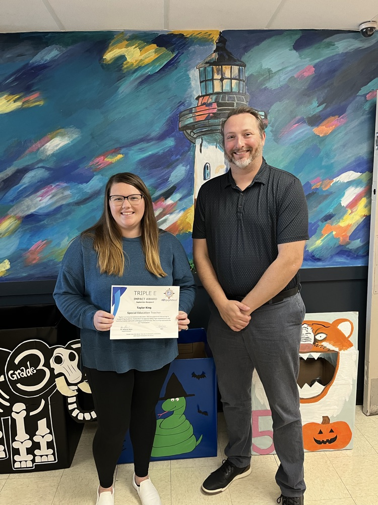 Mrs king and Mr Johnson standing in front of a painting of a lighthouse