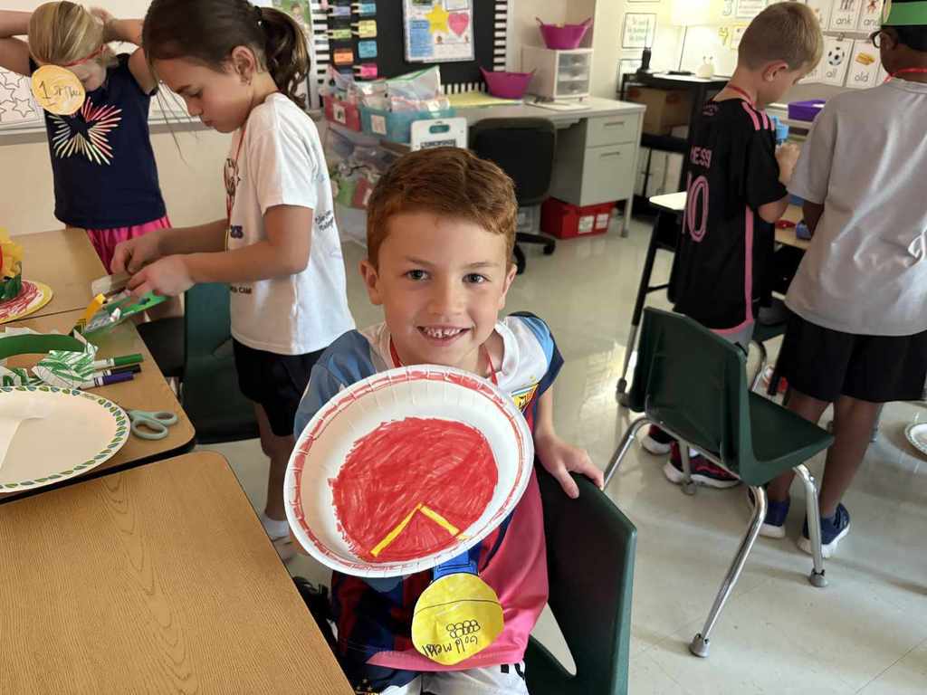2nd Grader shows off his Spartan shield and Olympic medal.