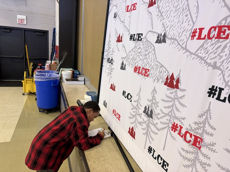 student in red and black flannel writing on a worksheet