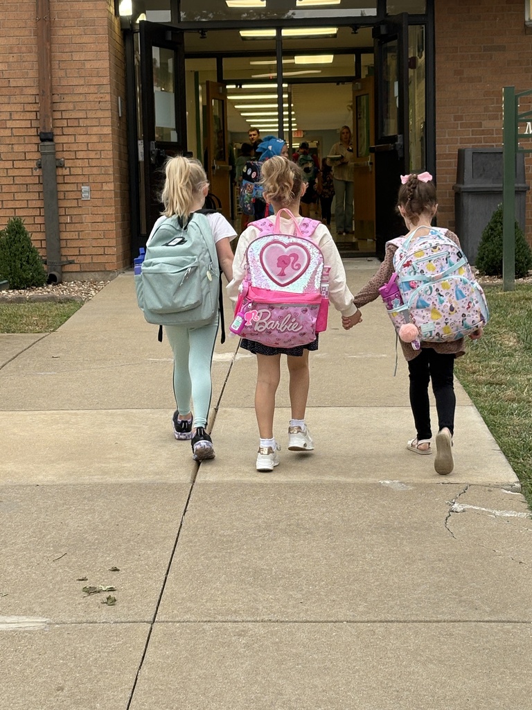 3 students walking into the building holding hands
