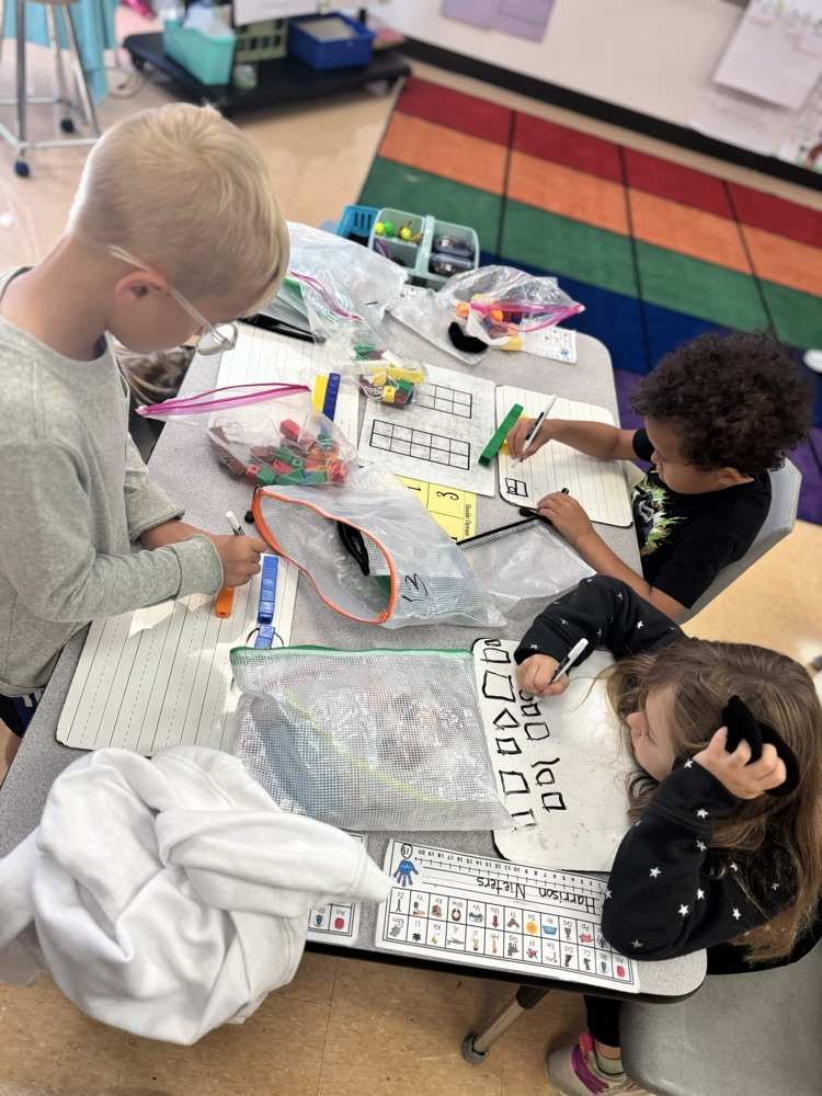 three first grade students hard at work, solving 9-5 with math tools.