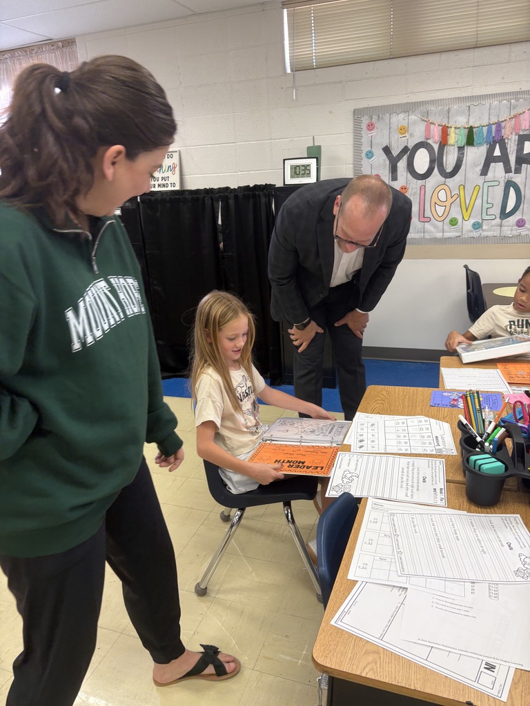 2nd grade student showing off her leadership binder to Dr. St. Pierre 
