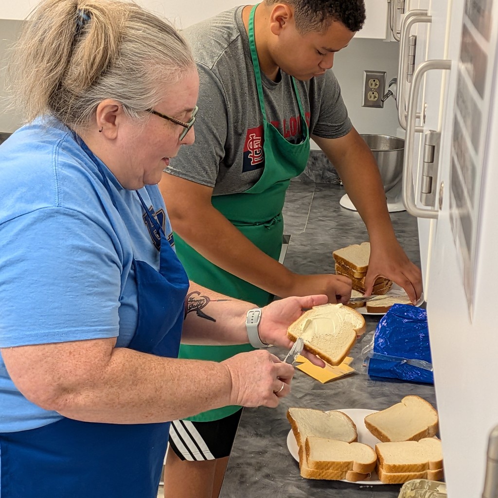 teacher and student team up to butter bread for grilled cheeses