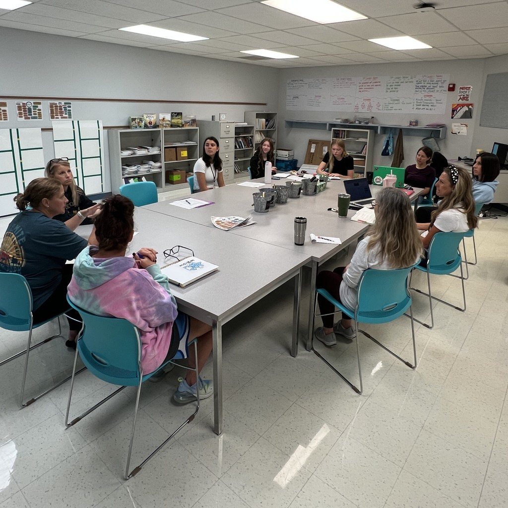 teachers and students around a meeting table engaged in discussion 