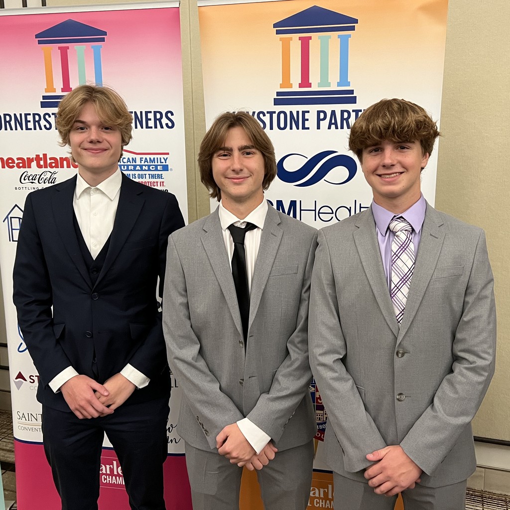 Students in suits pose in front of oganization banners