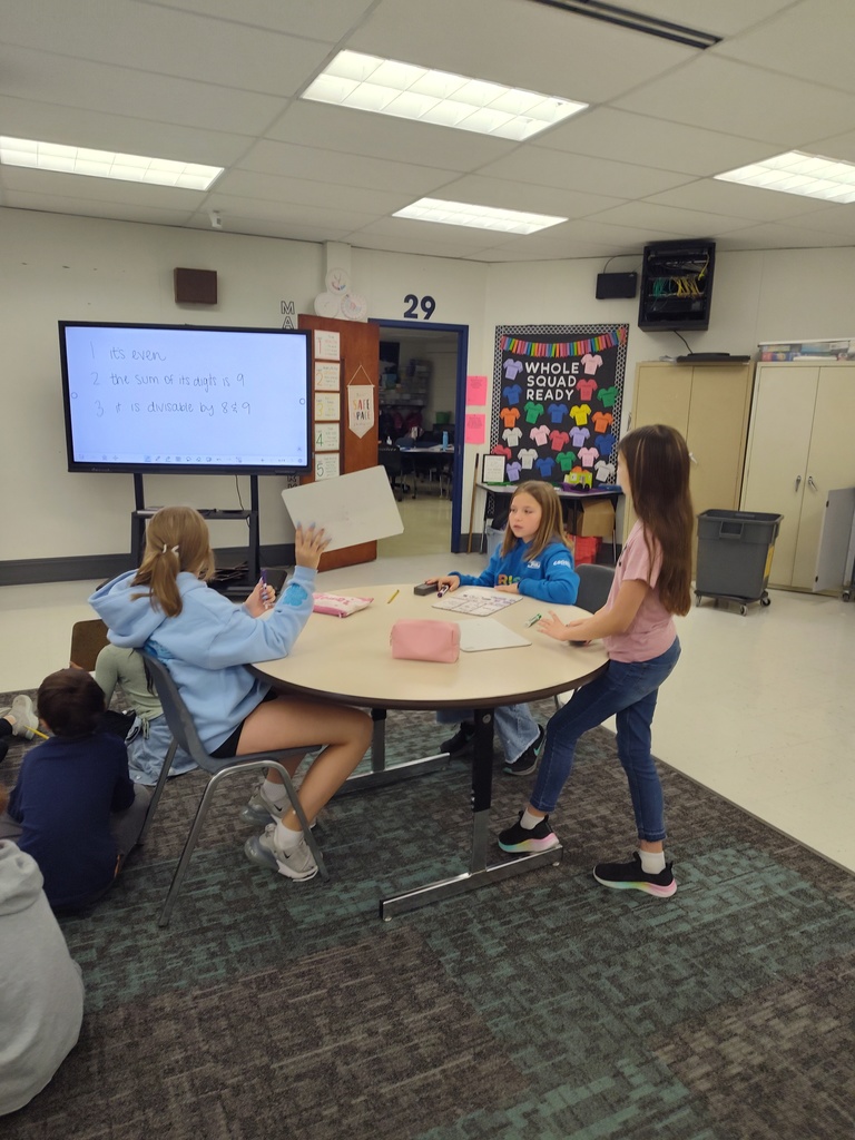students solve problems and hold up whiteboards with solutions