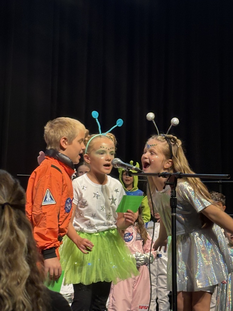 3 2nd-grade students singing at the microphone