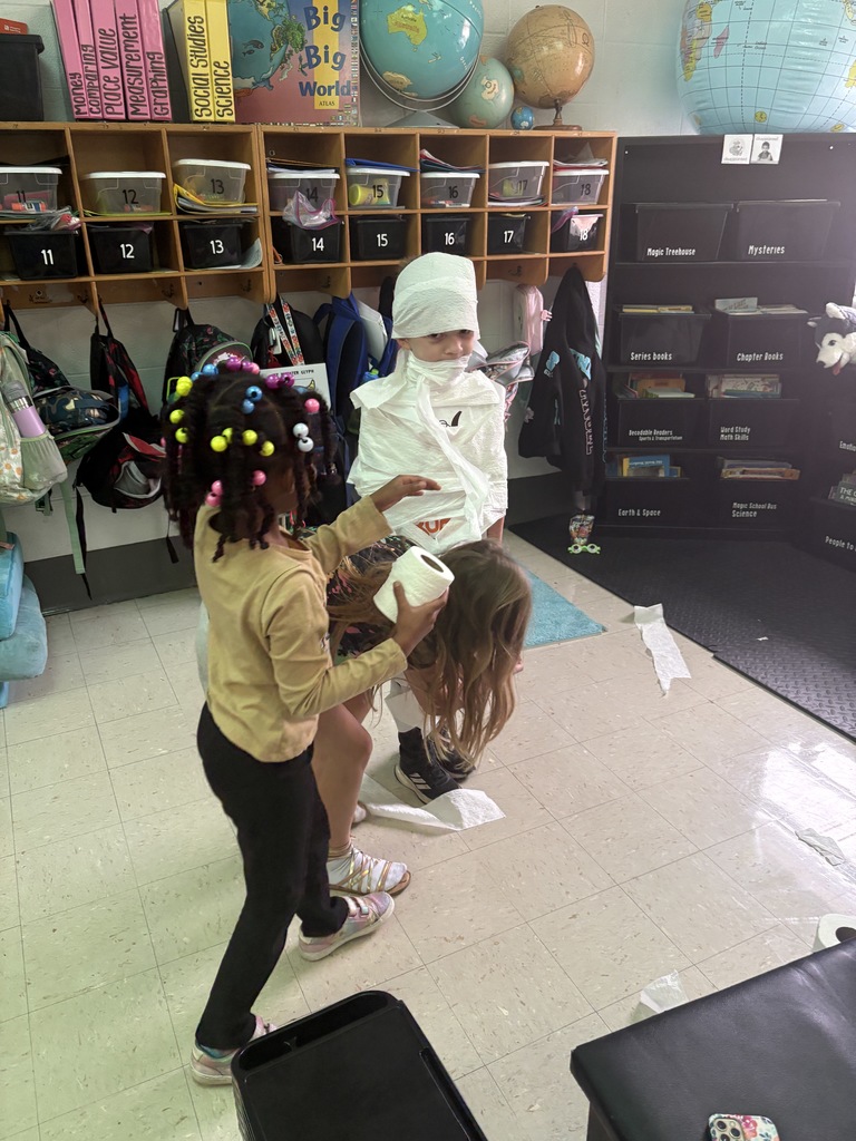 Students dressing a classmate up as a toilet paper mummy