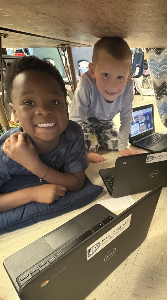 Two first-grade students working on their Chromebooks under their desk fort
